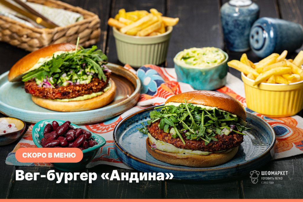 Вегетарианский бургер «Андина» с котлетой из фасоли и грецких орехов, гуакамоле, рукколой и сальсой из огурца, рядом картофель фри